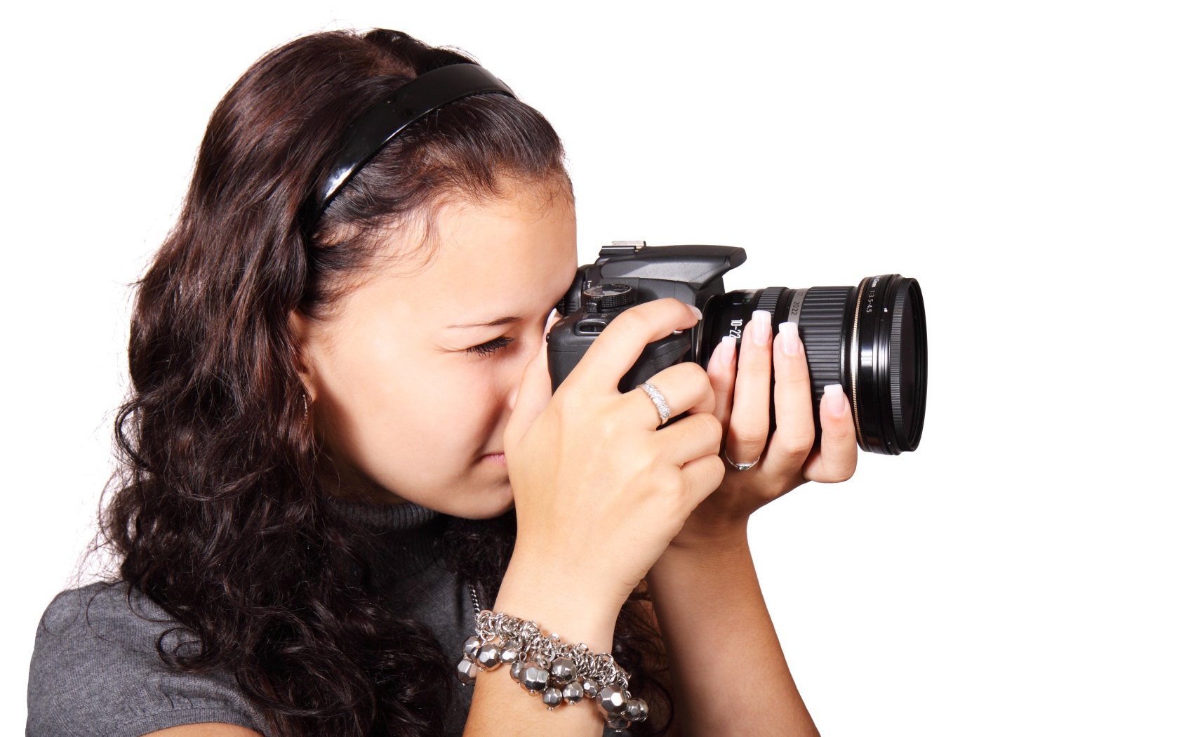 Молодая девушка шатенка с фотоаппаратом в руках на белом фоне