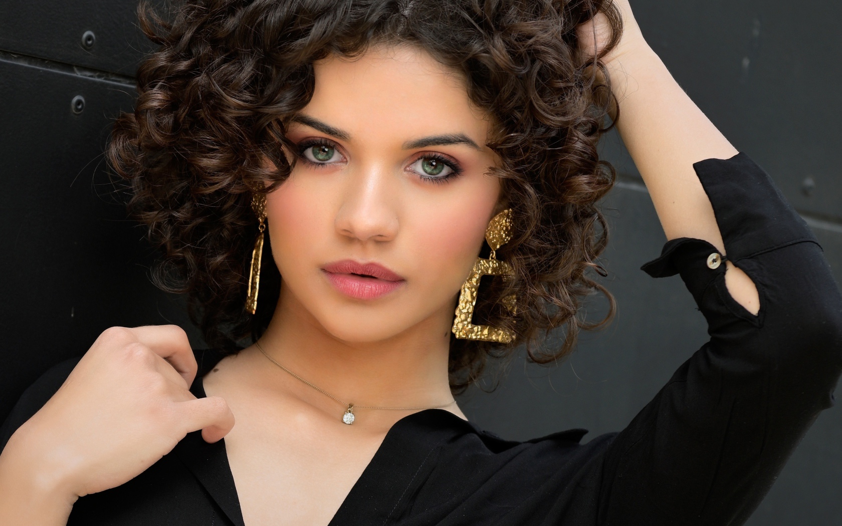 Кудрявая девушка с рукой в волосах в черной рубашке 