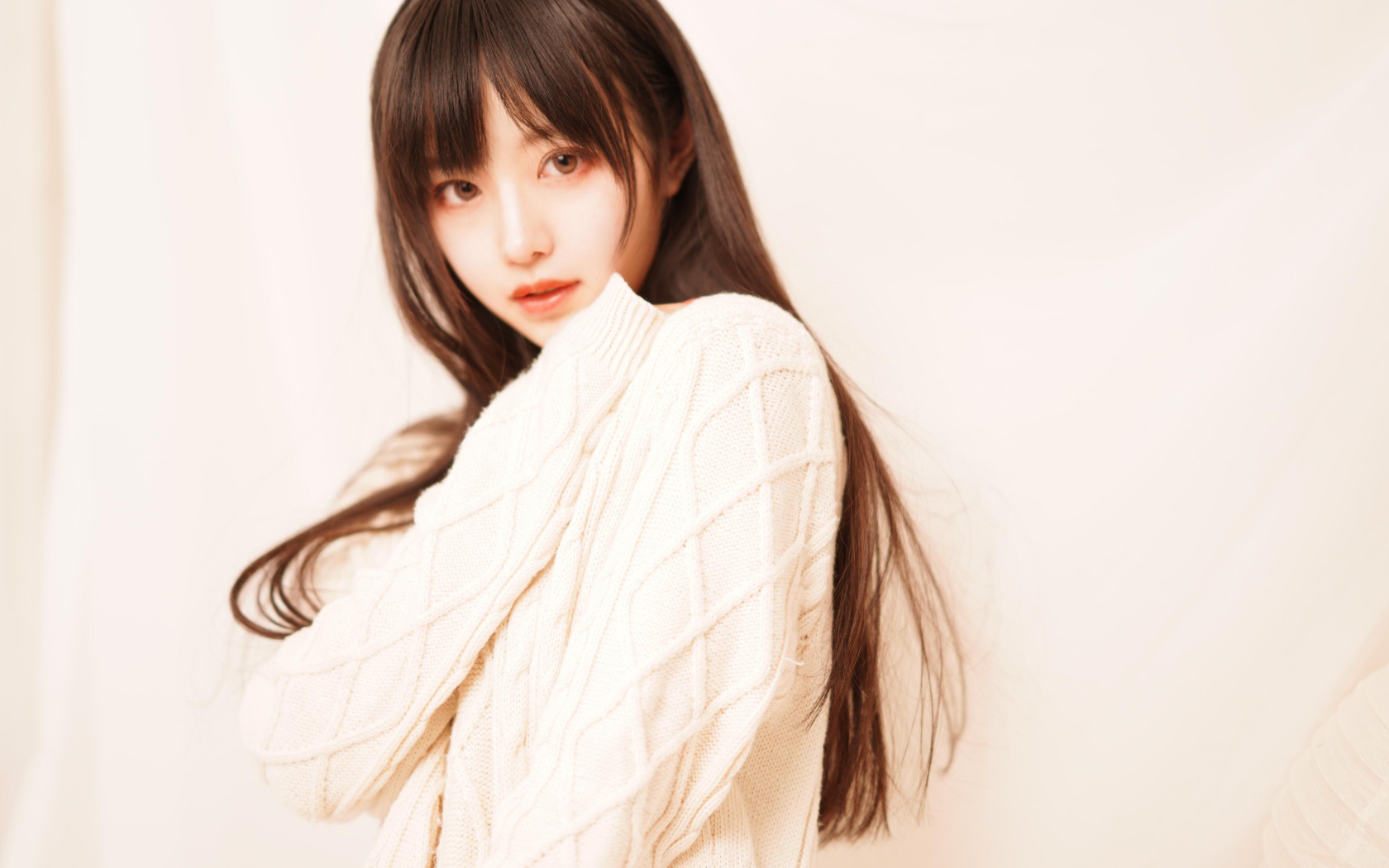 Милая азиатка в белом свитере на розовом фоне