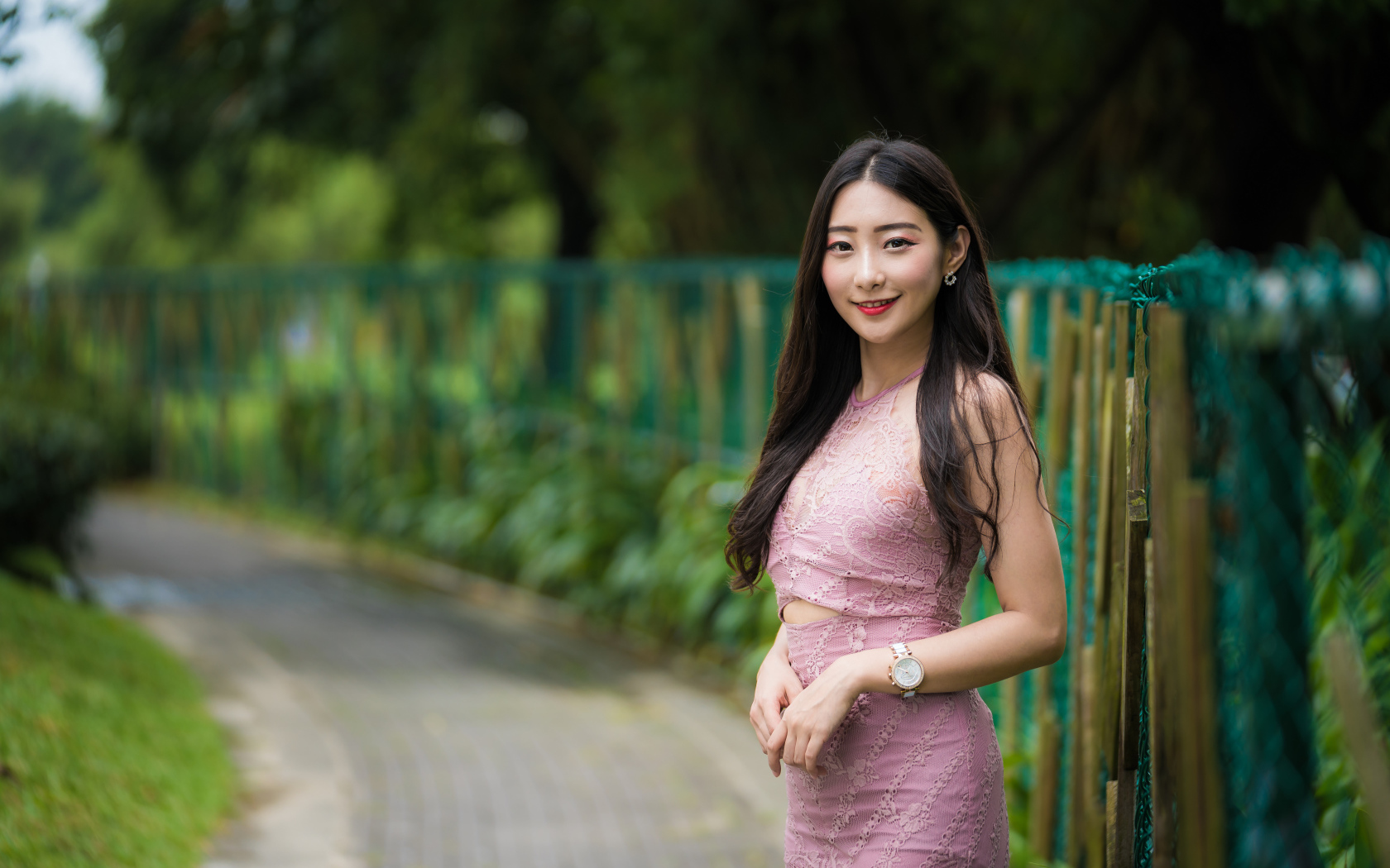 Милая улыбающаяся азиатка в костюме у забора