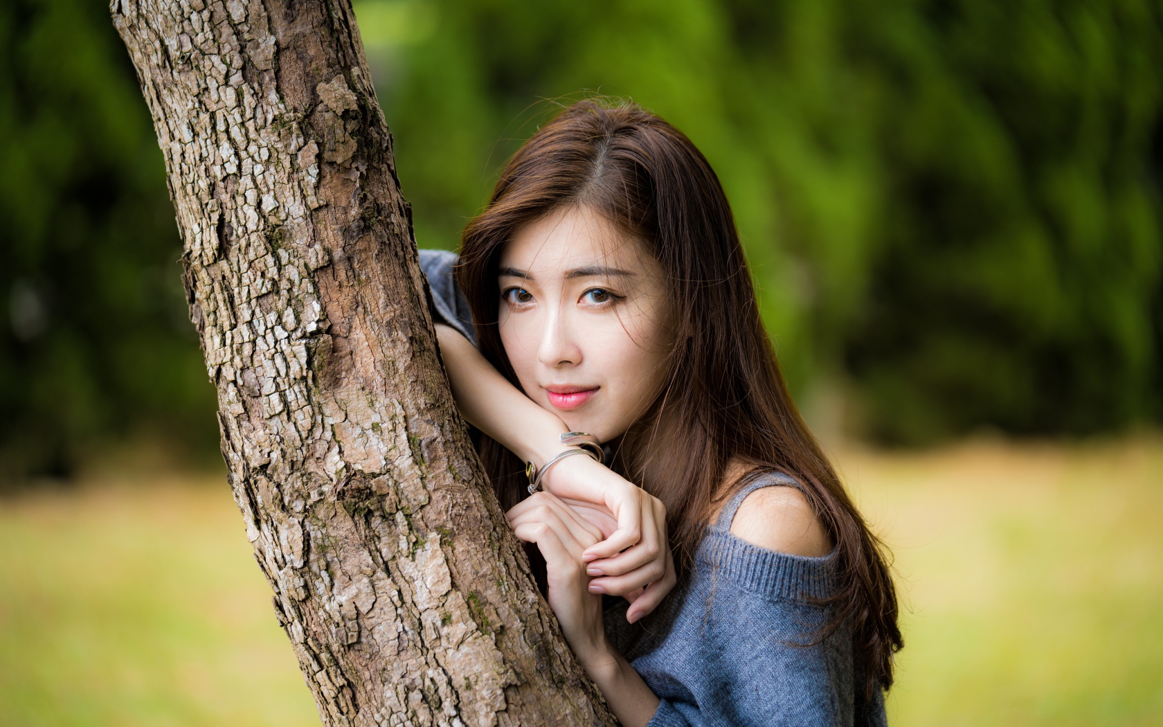 Мечтательная девушка азиатка стоит у дерева