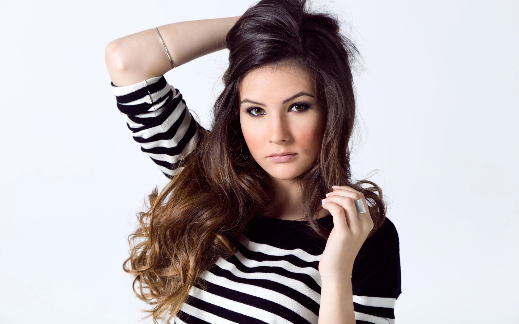 Девушка в полосатом свитере с рукой в волосах на белом фоне