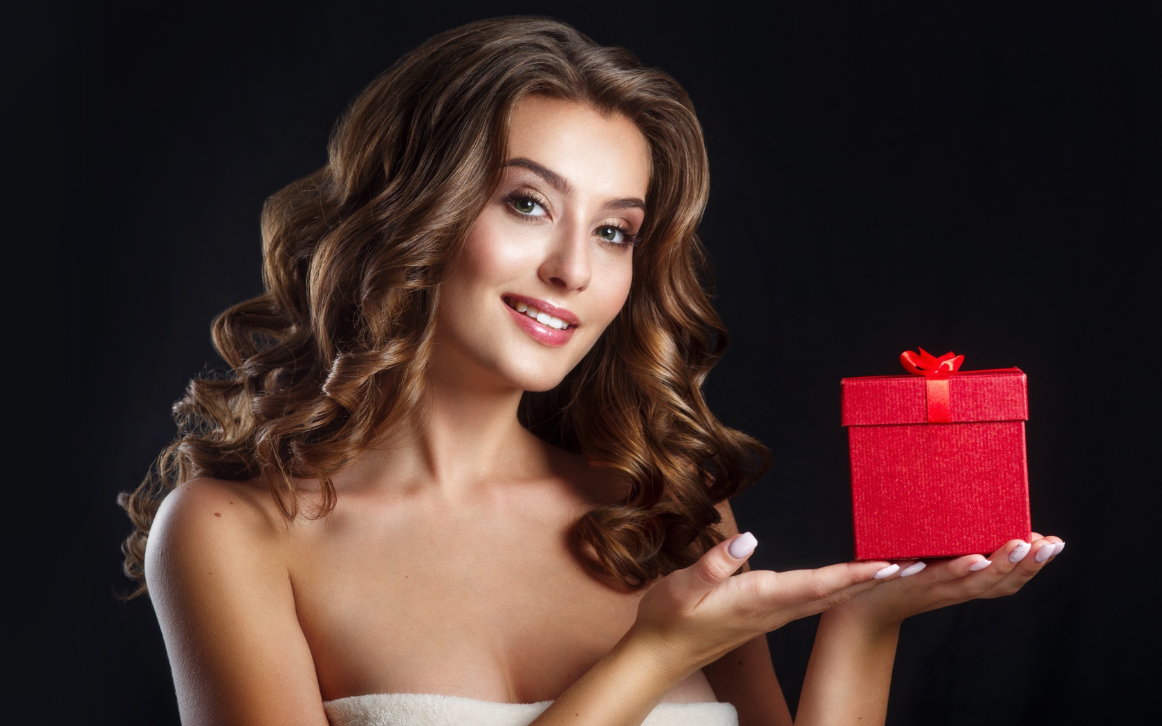 Девушка с красивыми волосами с подарком на руке 