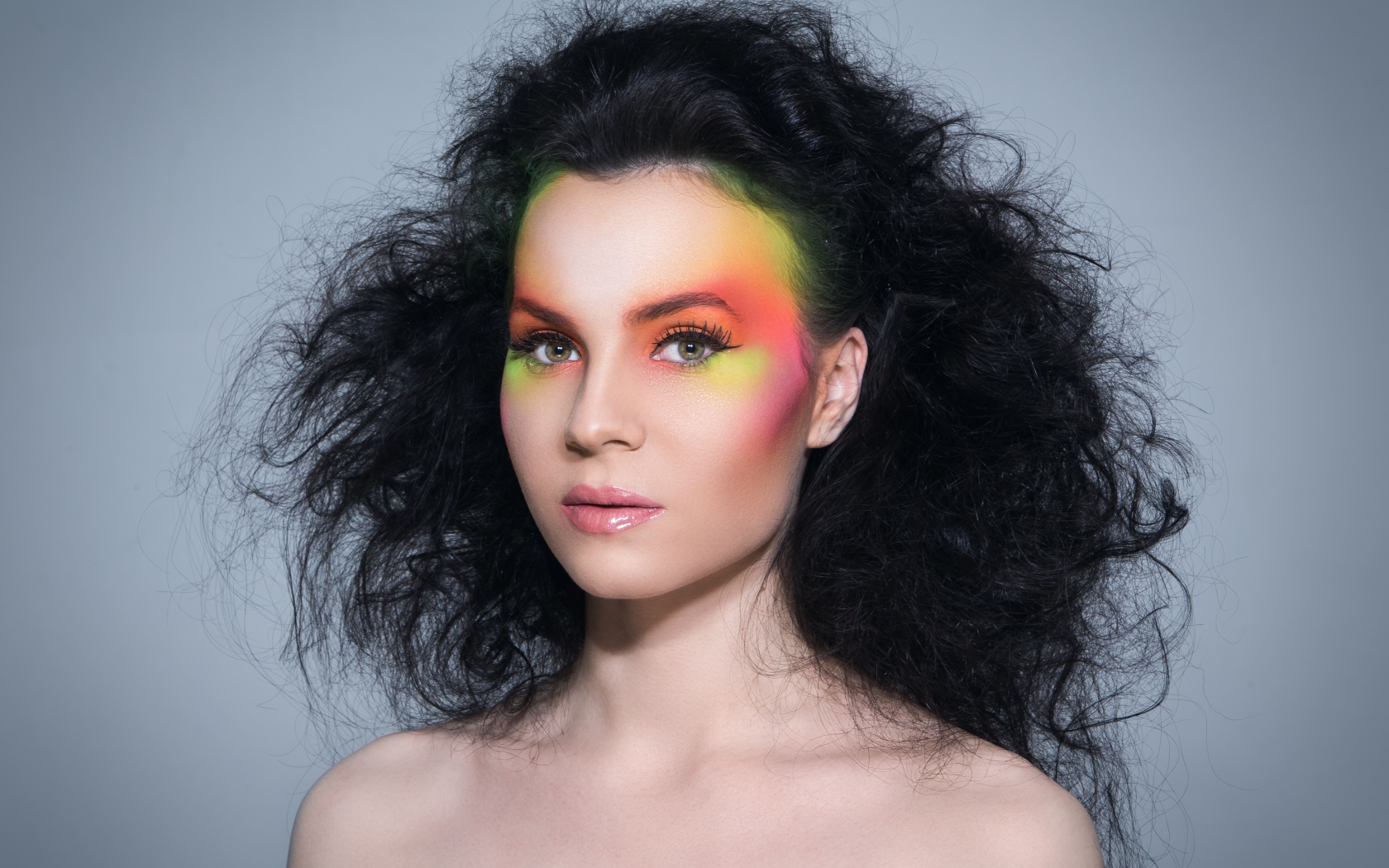 Девушка с начесом на волосах с ярким макияжем на сером фоне