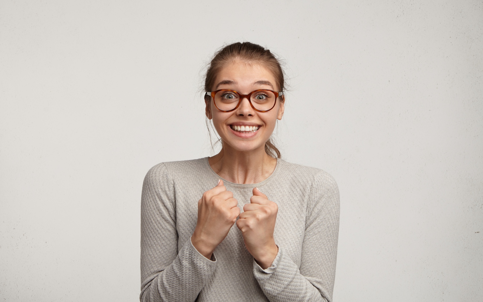 Радостная девушка в очках для зрения на сером фоне 