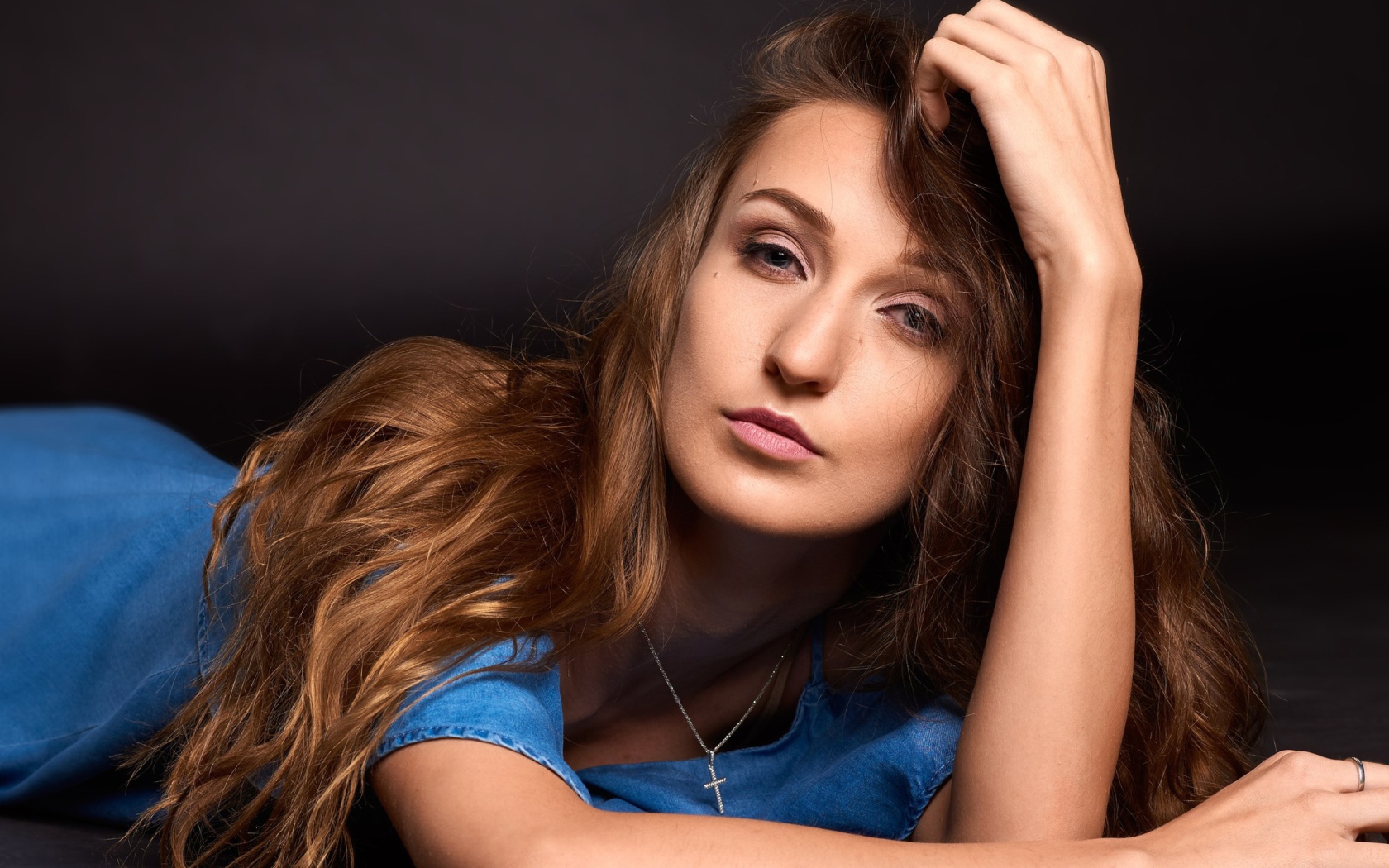 Длинноволосая шатенка лежит на полу в голубом платье 