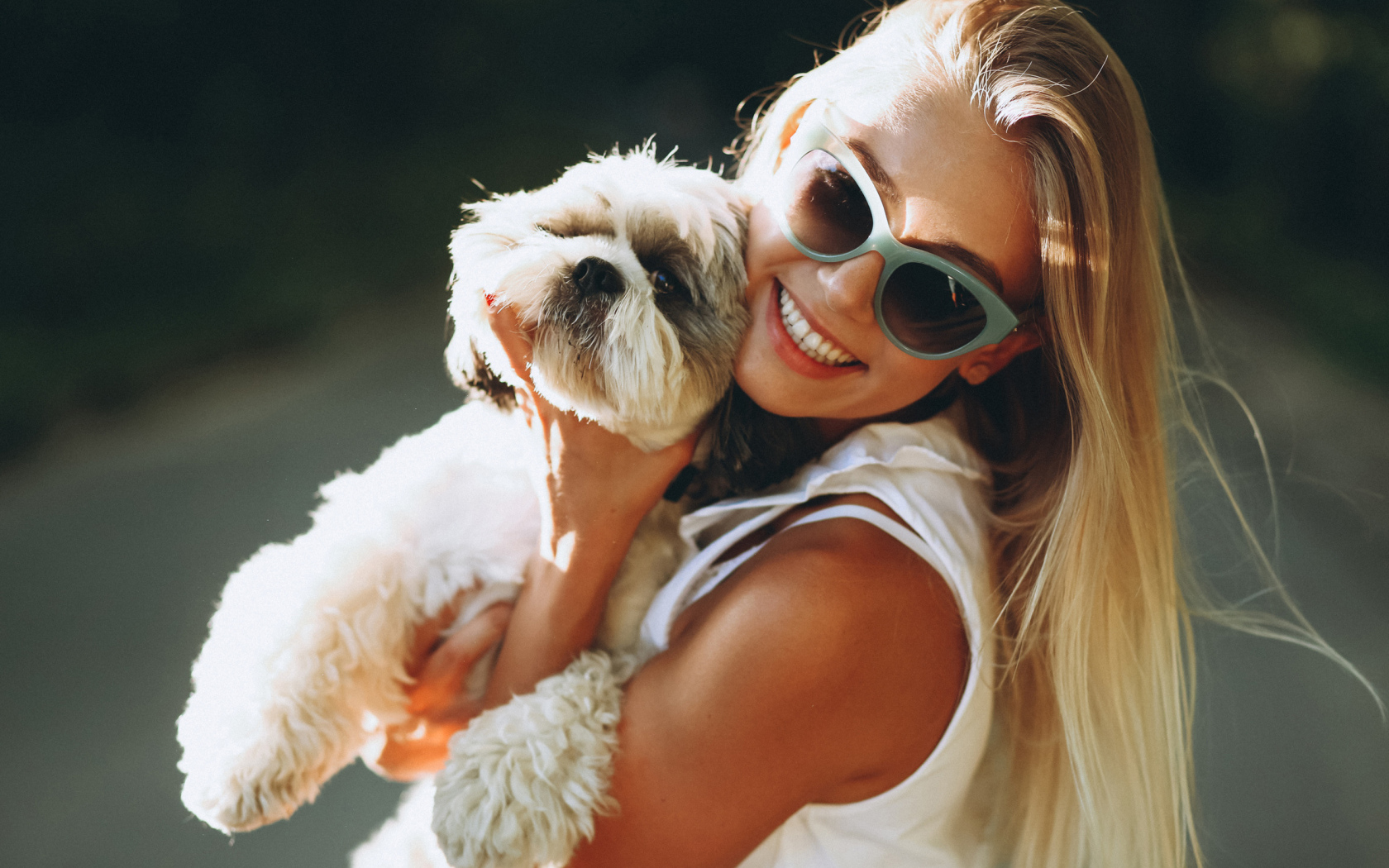 Улыбающаяся девушка в солнечных очках с собакой на руках