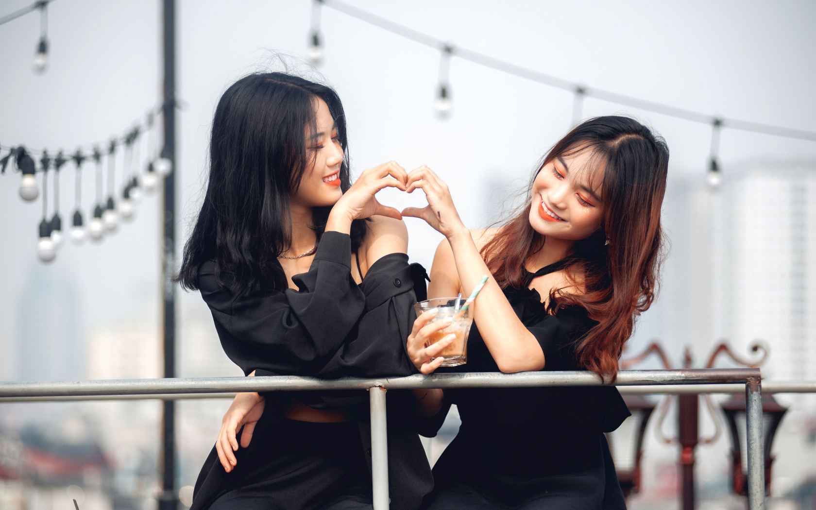 Две девушки азиатки делают сердце руками 
