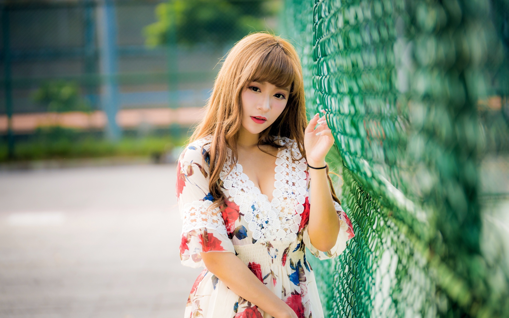 Молодая азиатка в платье у зеленой сетке 