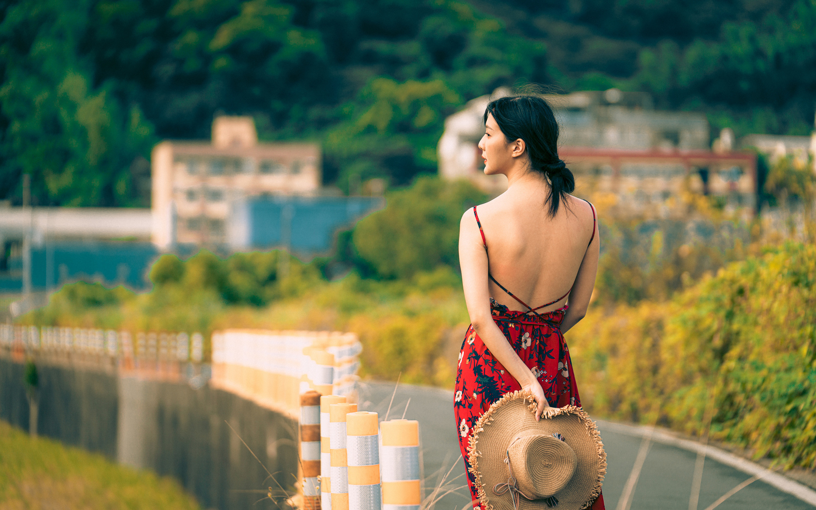 Молодая девушка азиатка в сарафане со шляпой в руке 