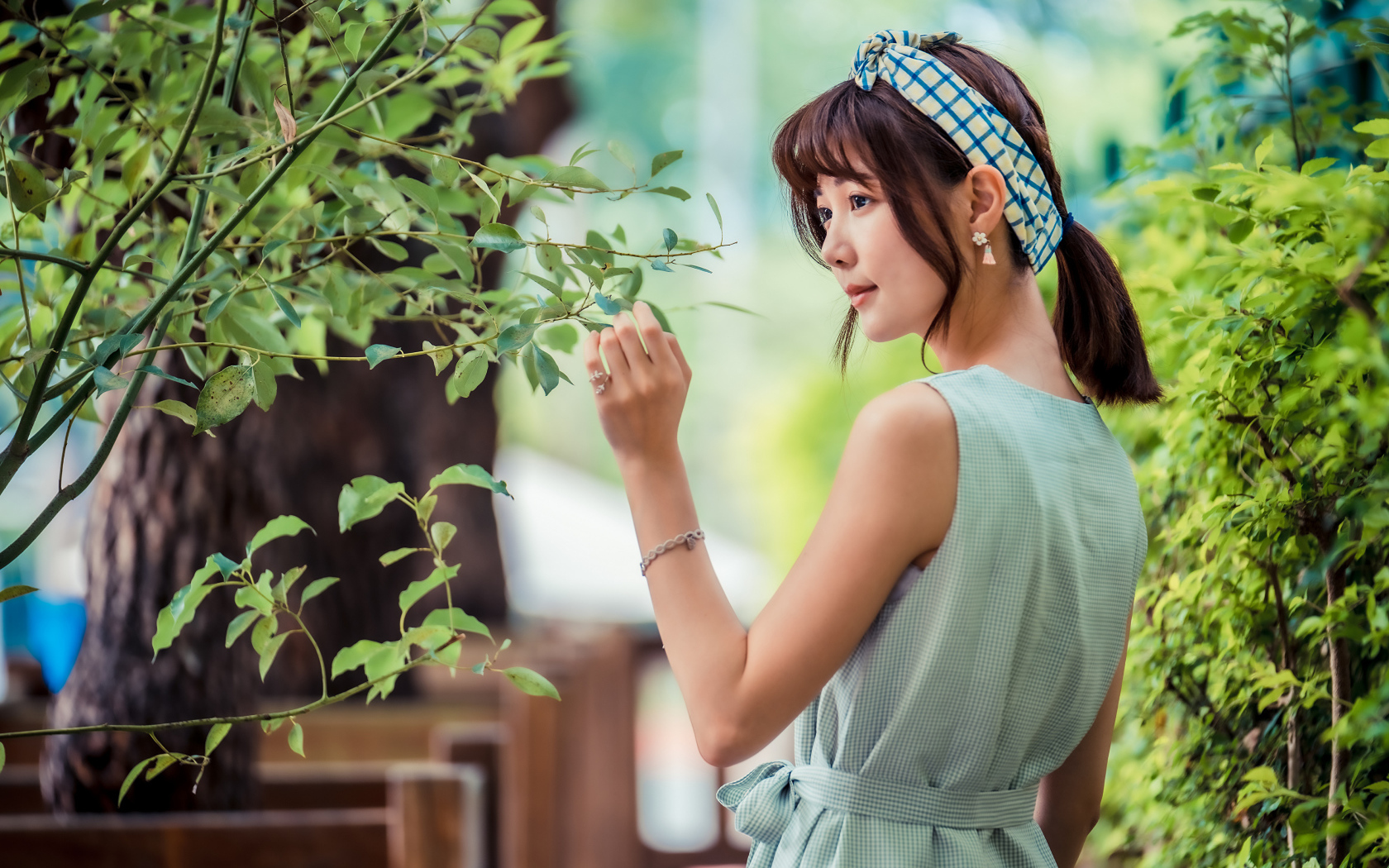 Молодая девушка азиатка с повязкой на голове у дерева 