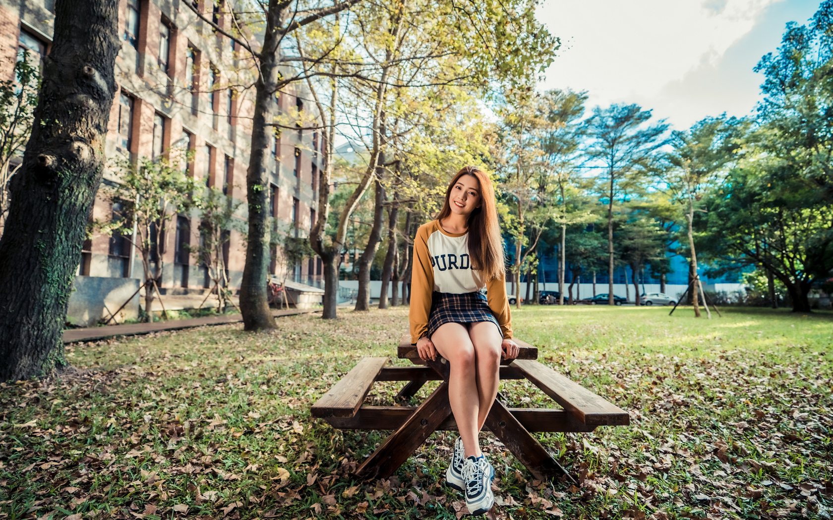 Молодая азиатка сидит на деревянном столе в парке 