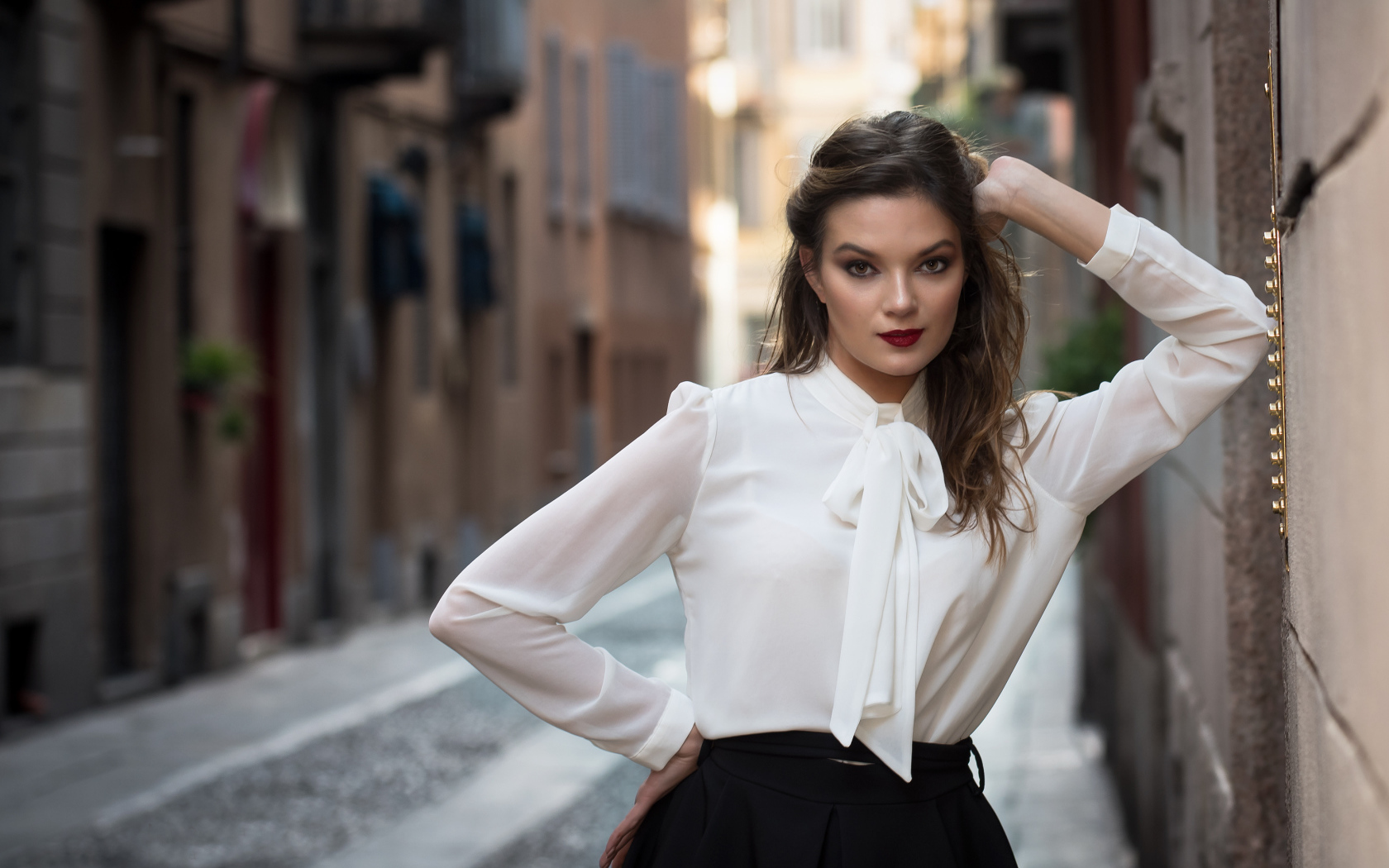 Молодая девушка в белой рубашке у стены