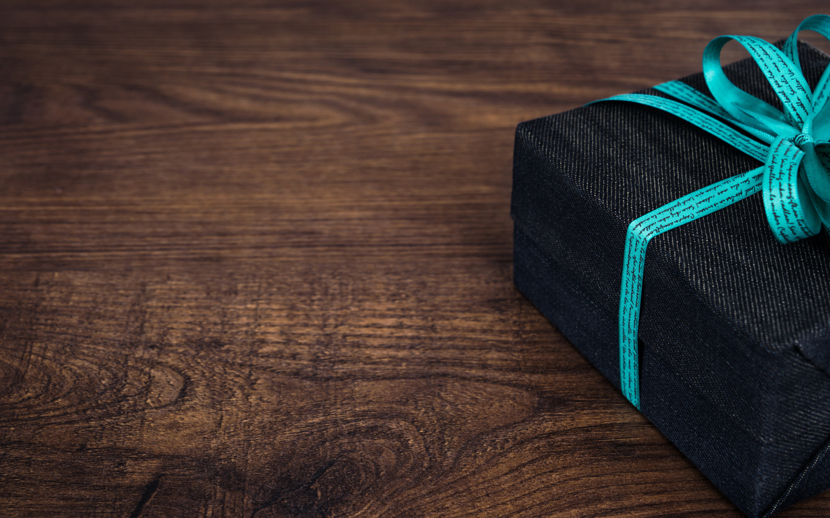 Подарок с синим бантом на деревянном столе 