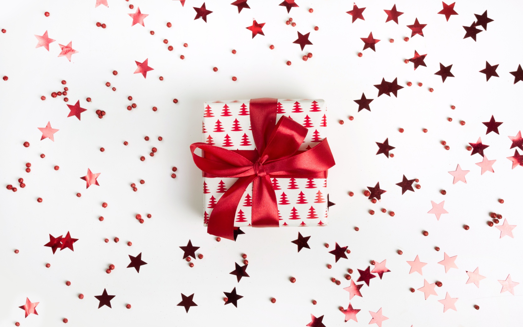 Подарок с красным бантом на белом фоне со звездочками