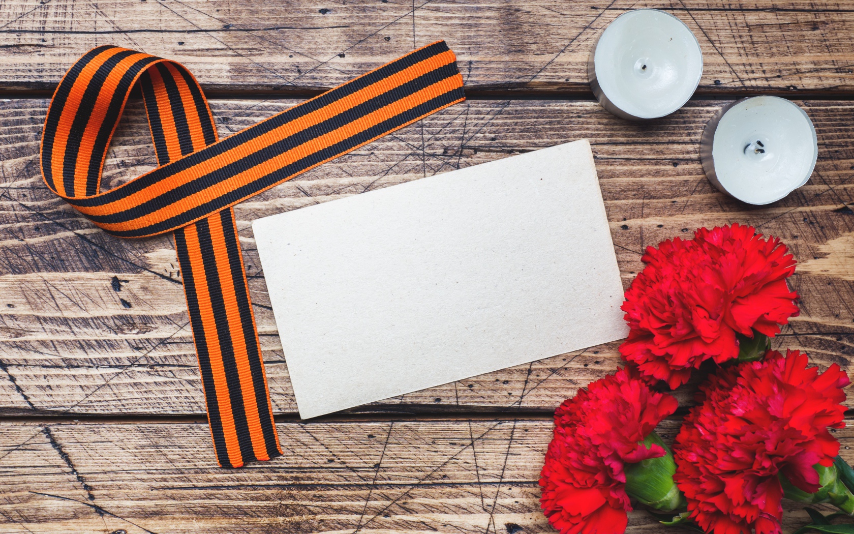 Красные гвоздики, георгиевская лента и свечи на столе, шаблон для открытки на 9 мая День победы