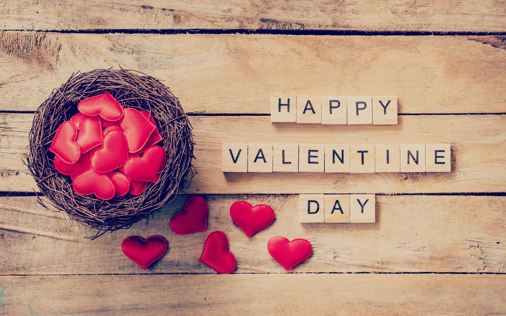Кубики и гнездо с сердечками на деревянном столе на День Святого Валентина