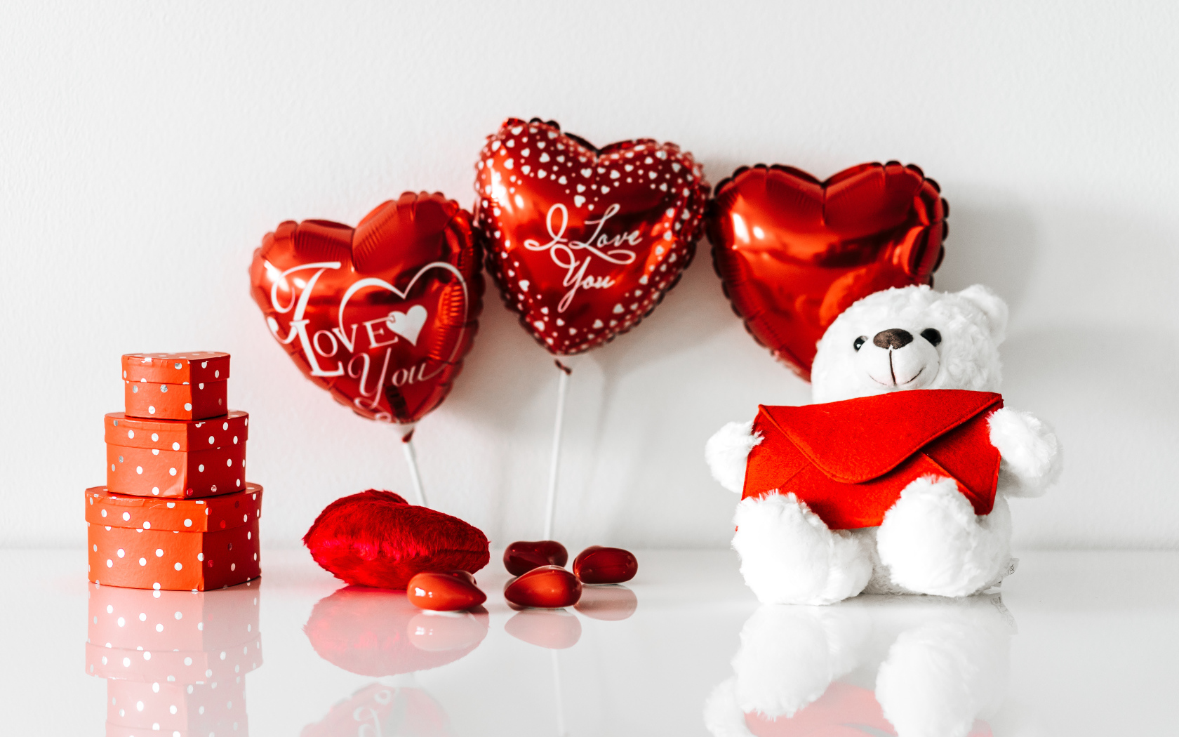 Белый мишка с подарками и шариками у стены