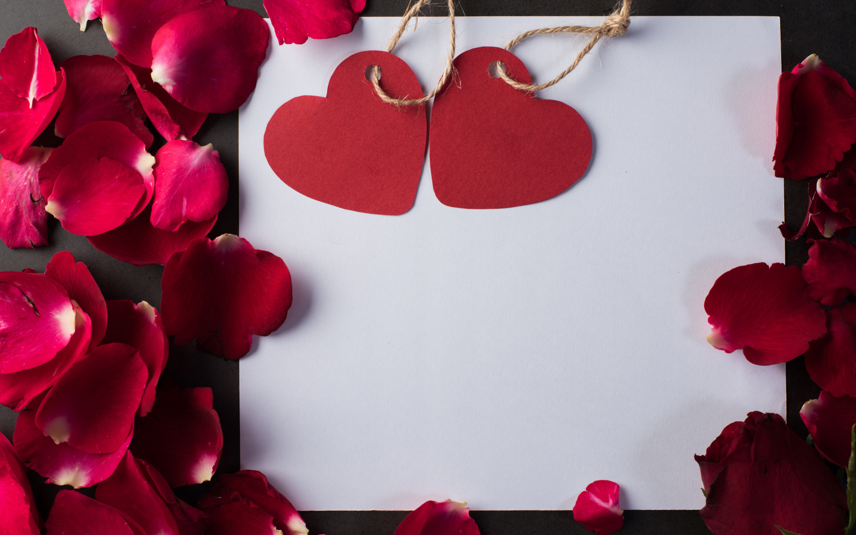 Белый лист бумаги с сердечками и лепестками роз 