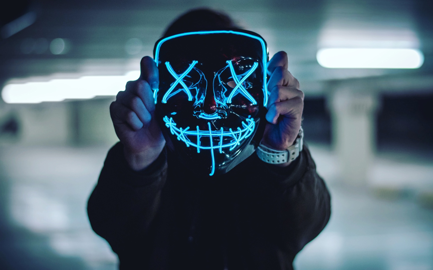 Неоновая маска анонима в руках у парня 