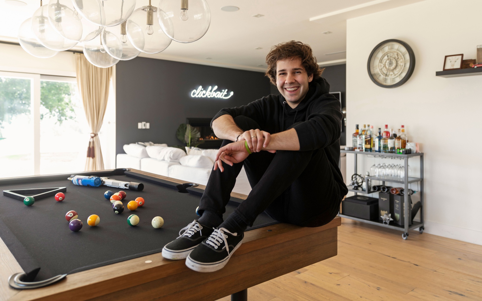 Молодой блогер, юморист  Дэвид Добрик сидит на столе