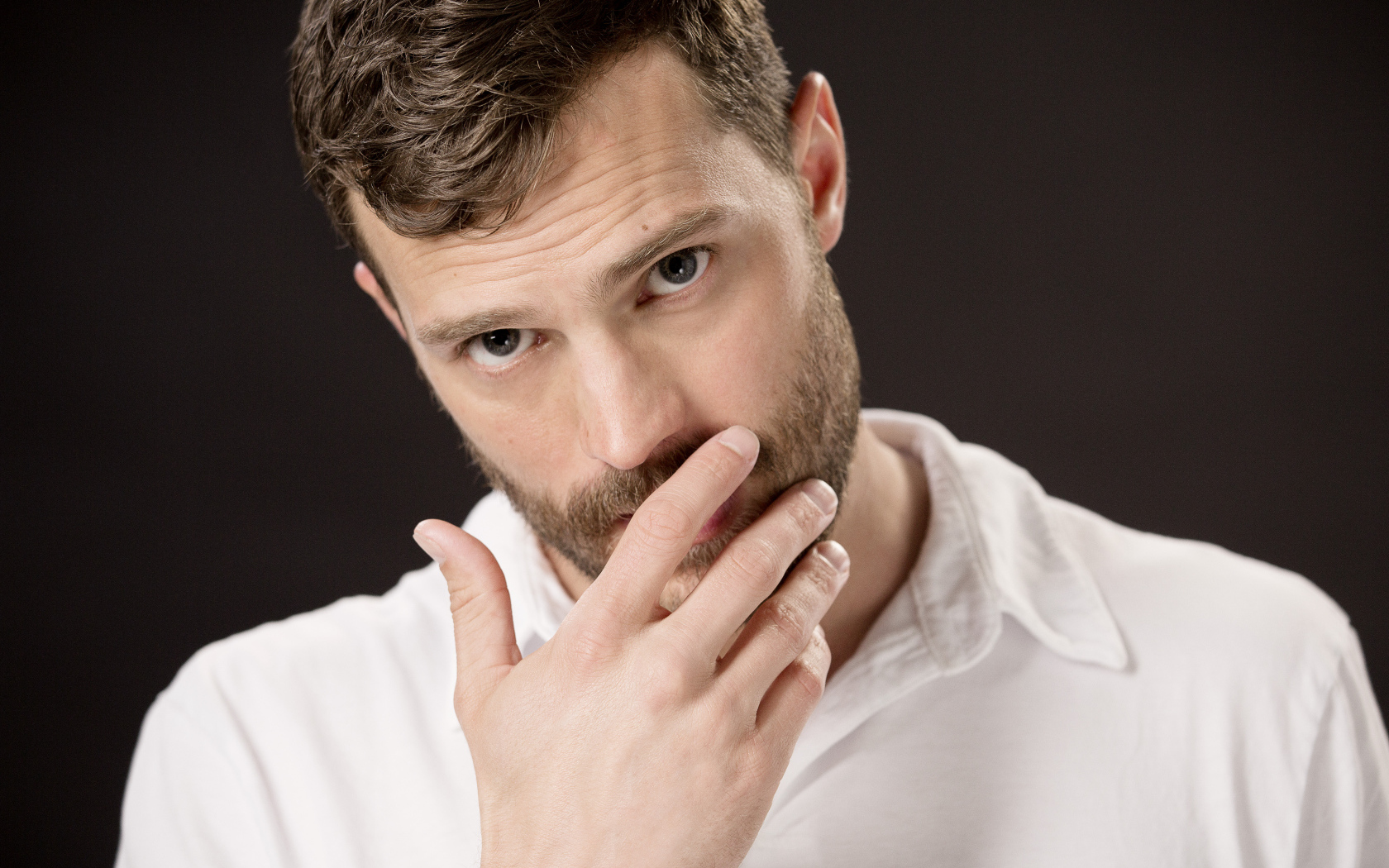 Молодой мужчина, актер Джейми Дорнан с рукой у лица