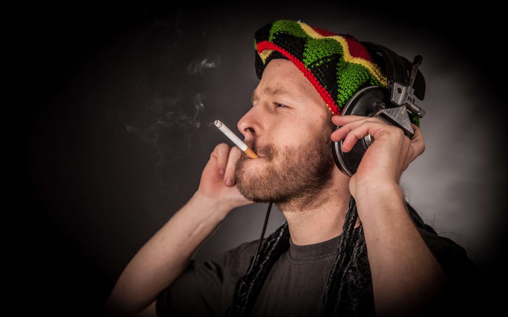 Мужчина растаман в наушниках с сигаретой 