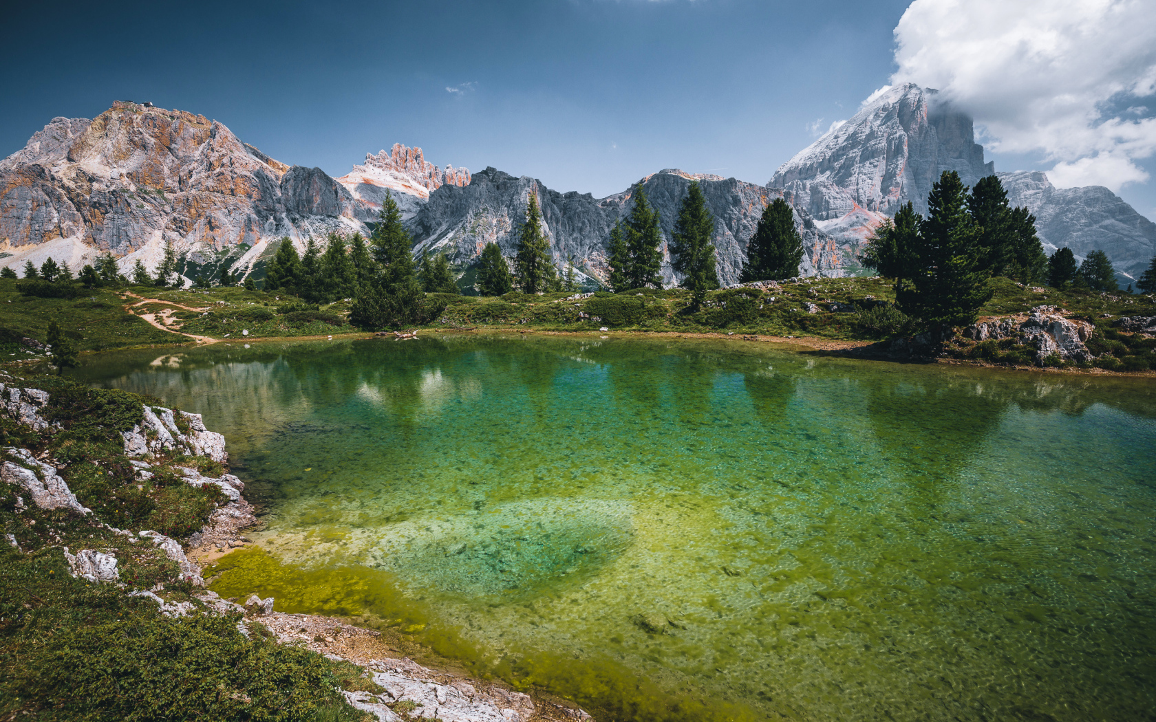Озеро у заснеженных гор под небом с белыми облаками