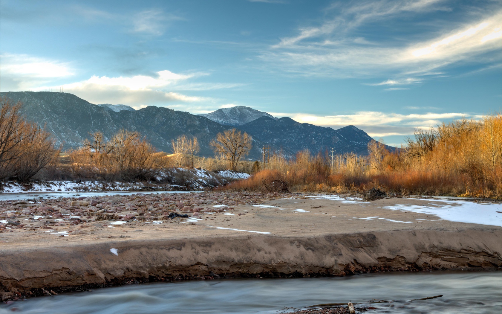 Каменный берег реки на фоне гор под голубым небом 