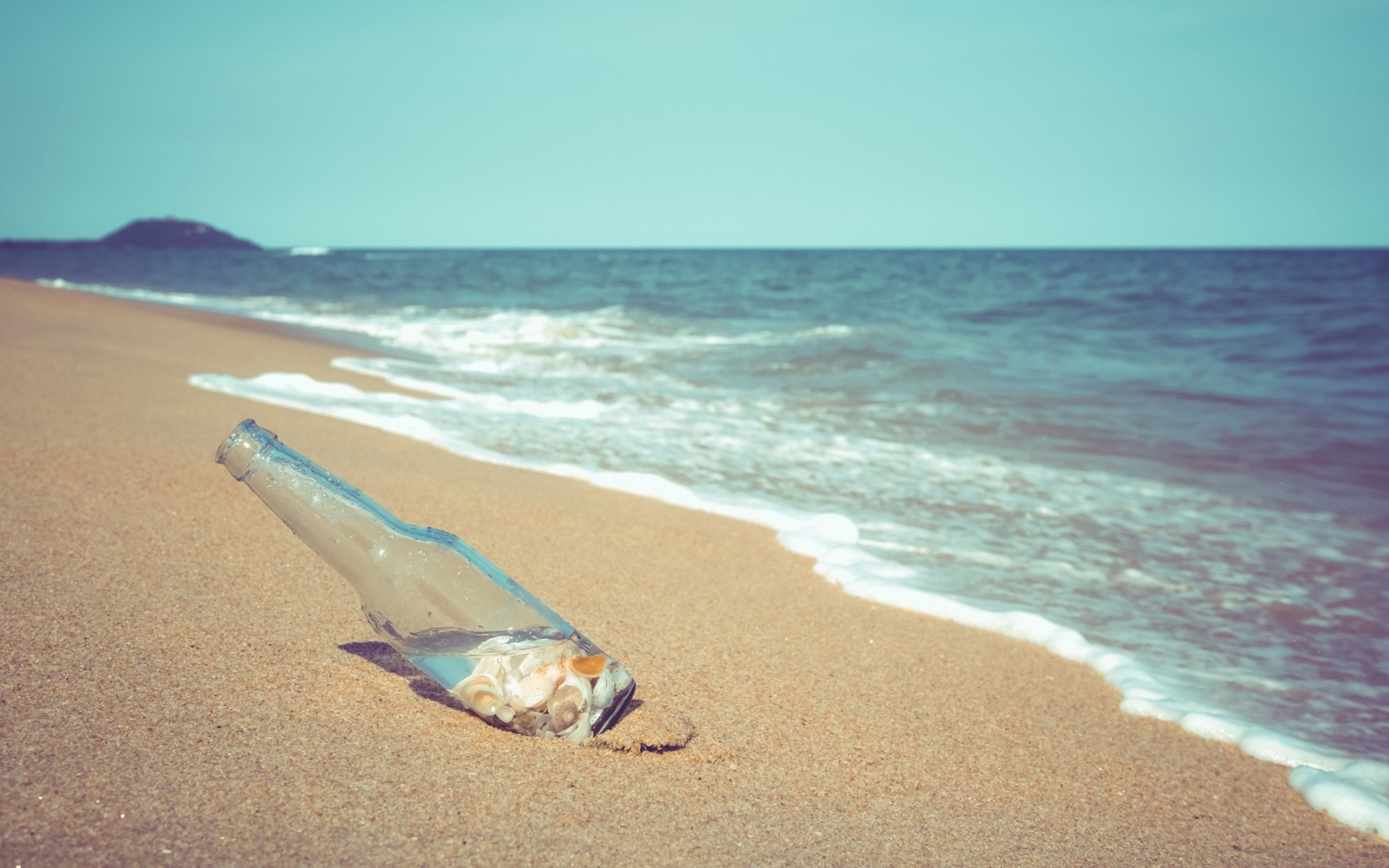 Бутылка с ракушками на песке у моря