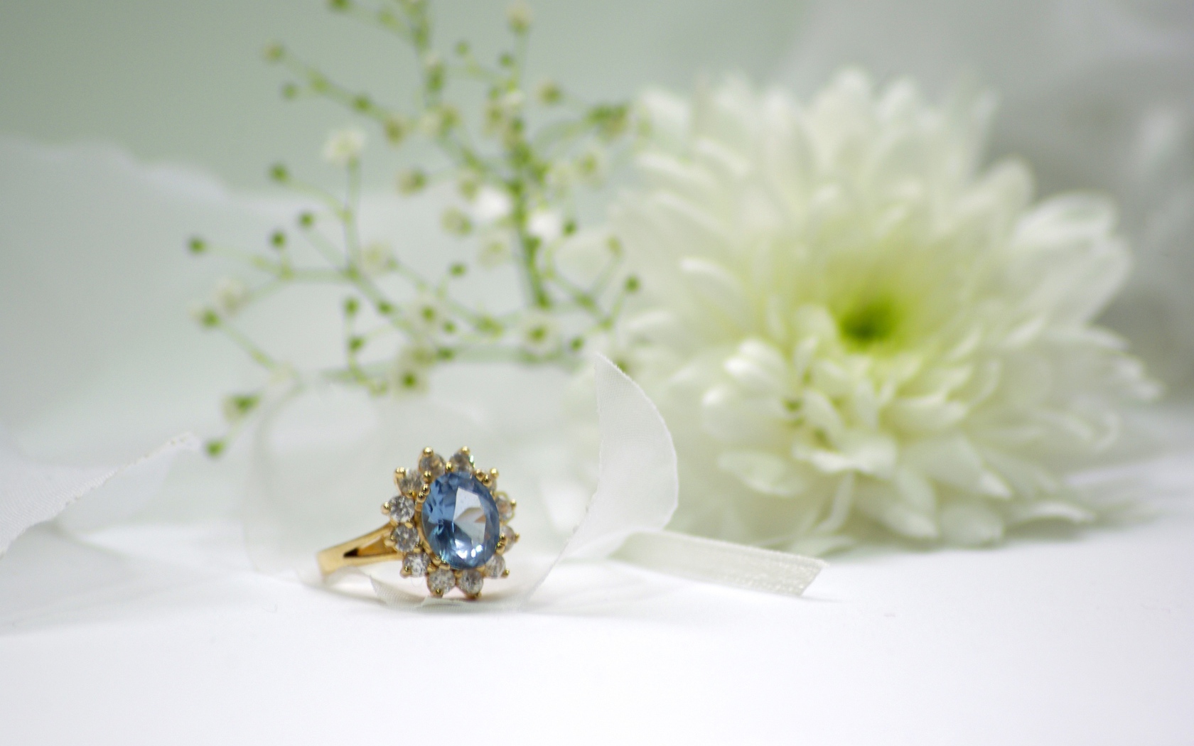 Дорогое кольцо с камнем на столе с белым цветком