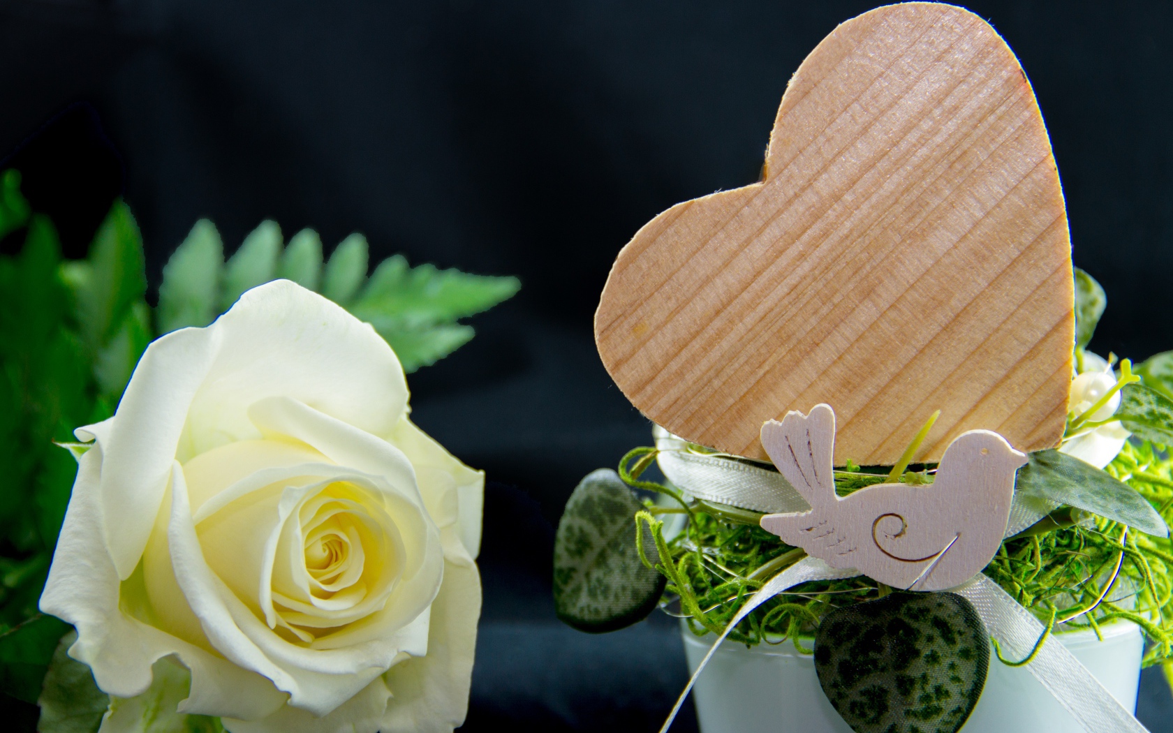 Деревянное сердце и белая роза на столе 