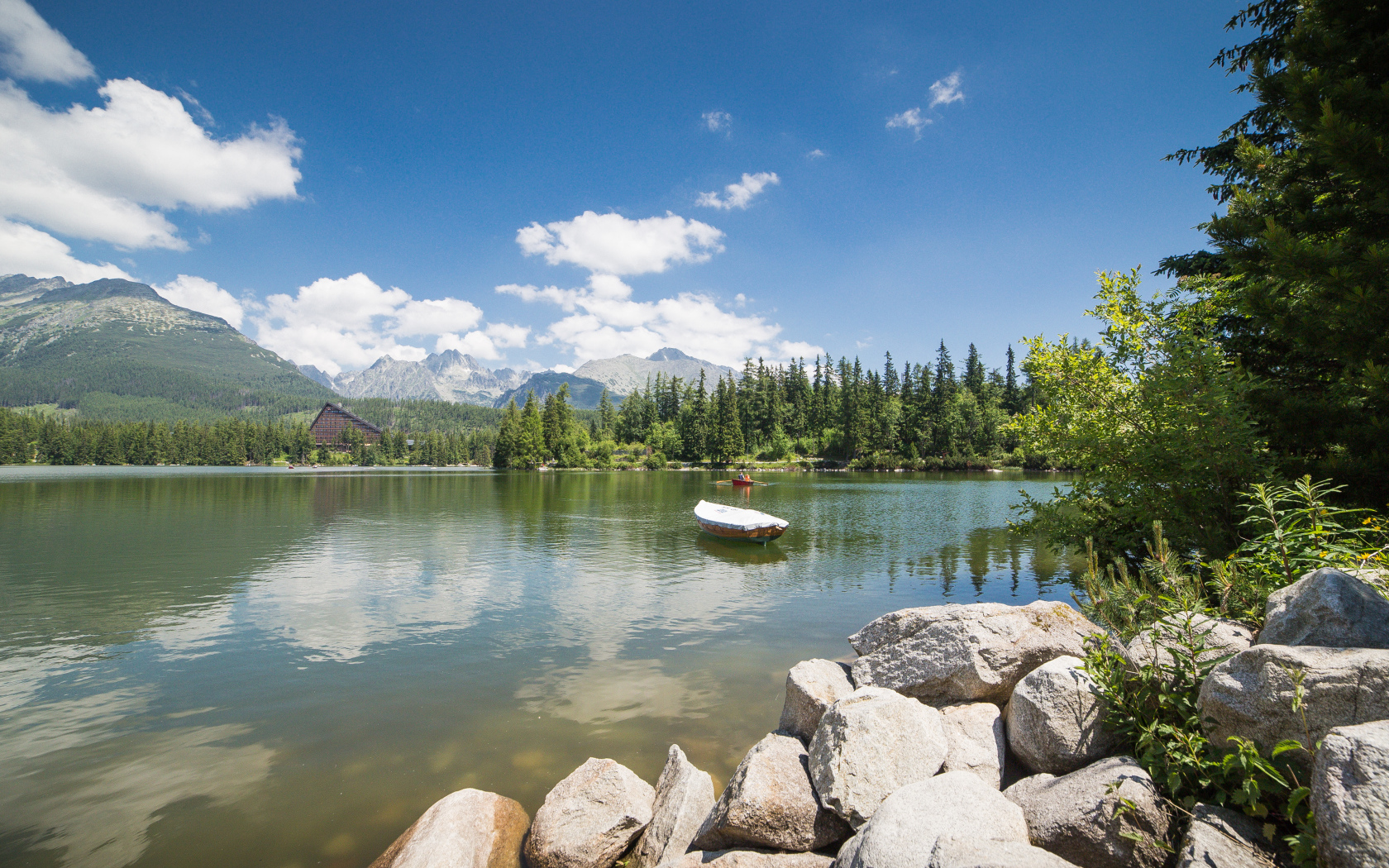 Лодка в озере на фоне гор под голубым небом
