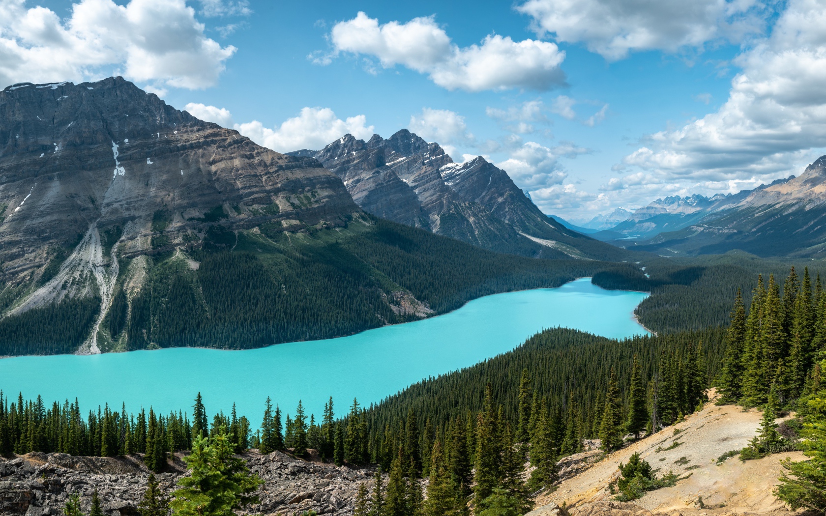 Тень от белых облаков на горном массиве у голубого озера