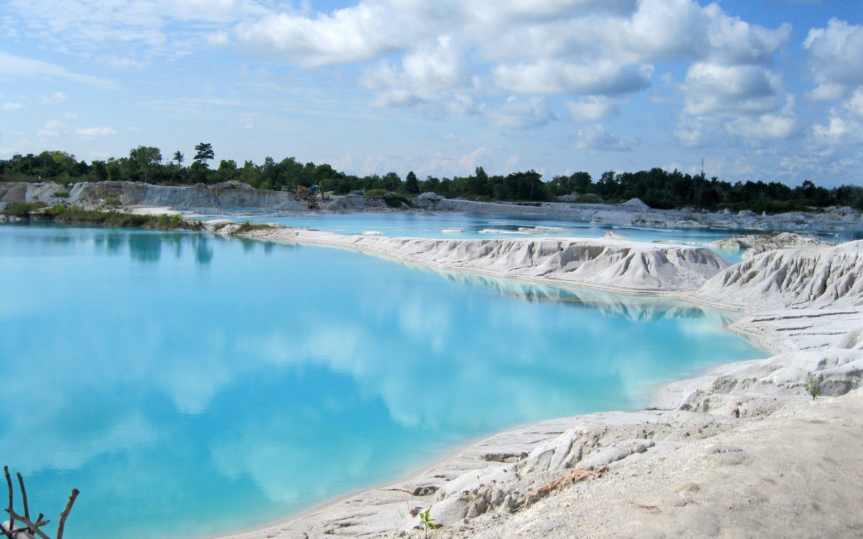 Белый песок на берегу водоема с голубой водой 