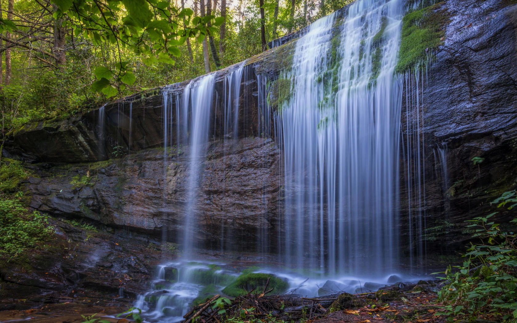 Холодная вода водопада стекает по мокрой скале