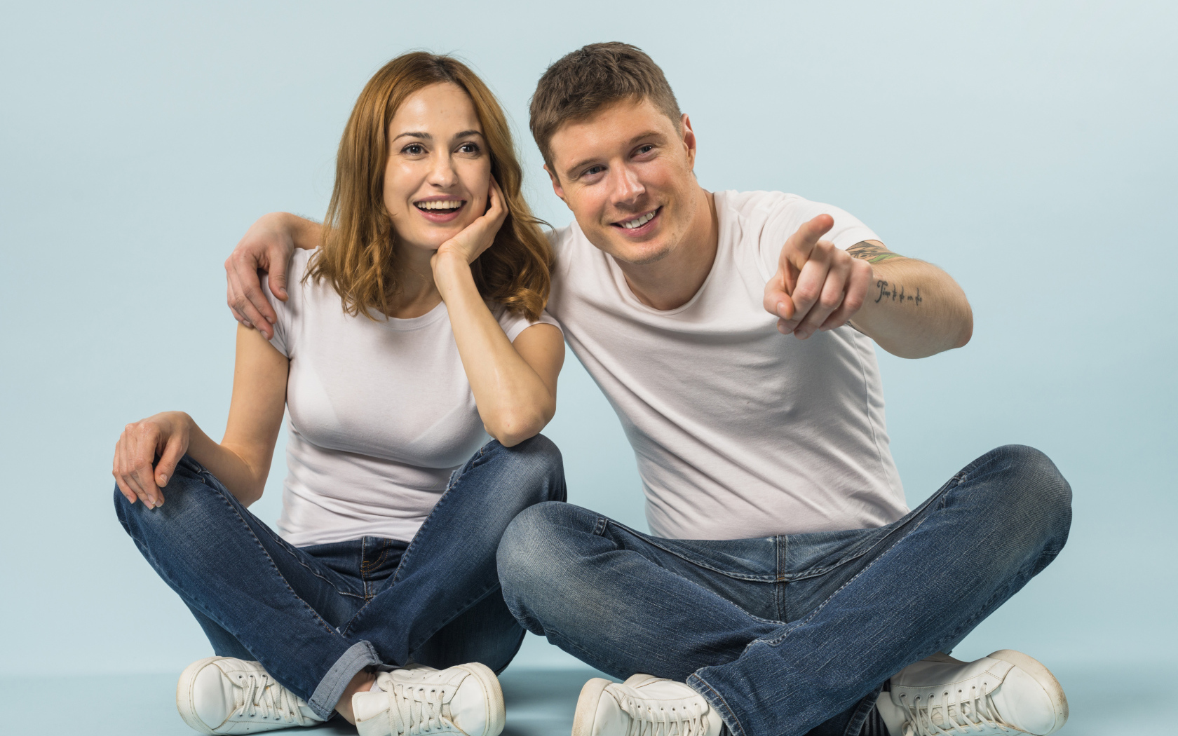Мужчина и девушка сидят на полу на голубом фоне