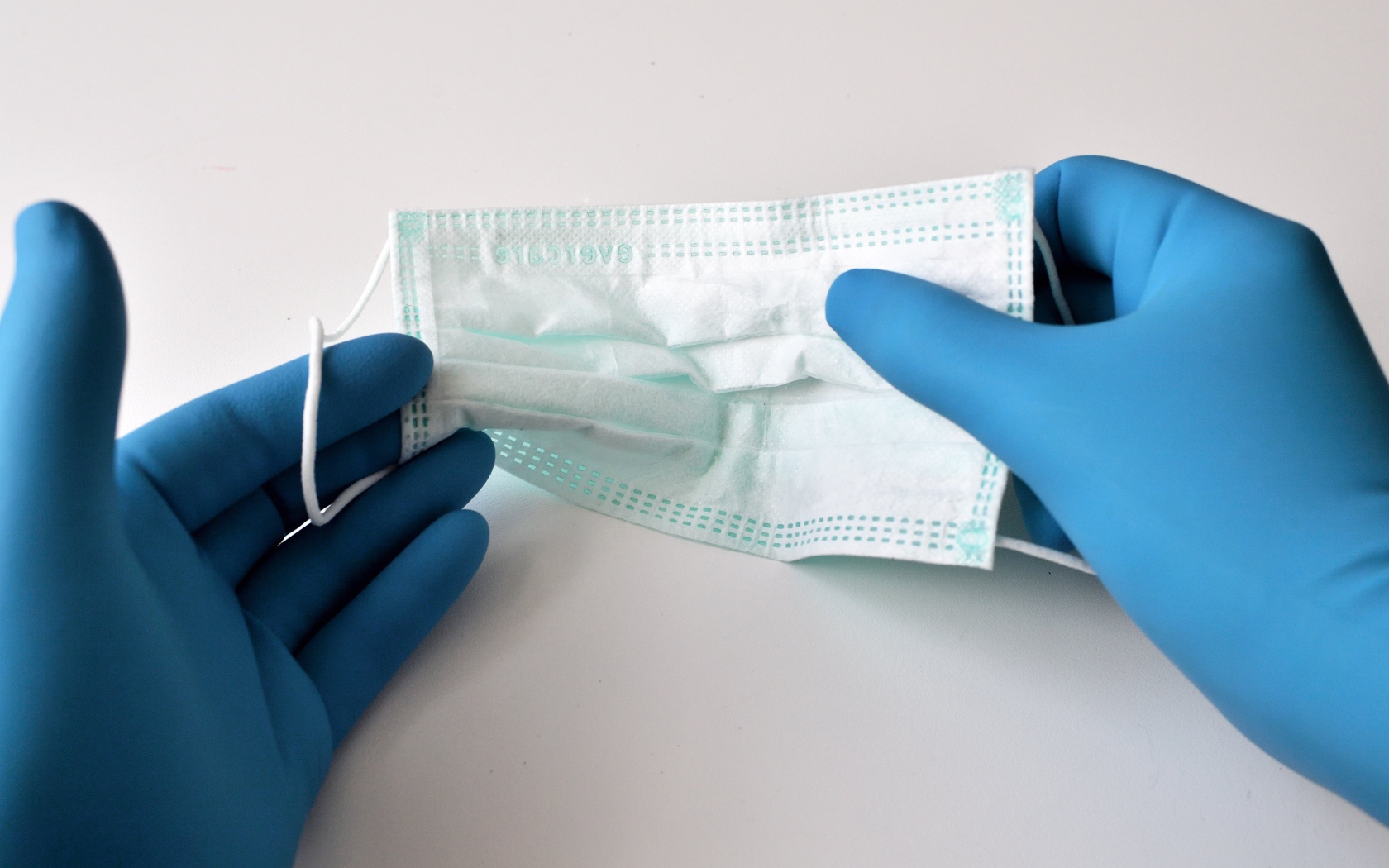 Руки в медицинских перчатках держат маску 