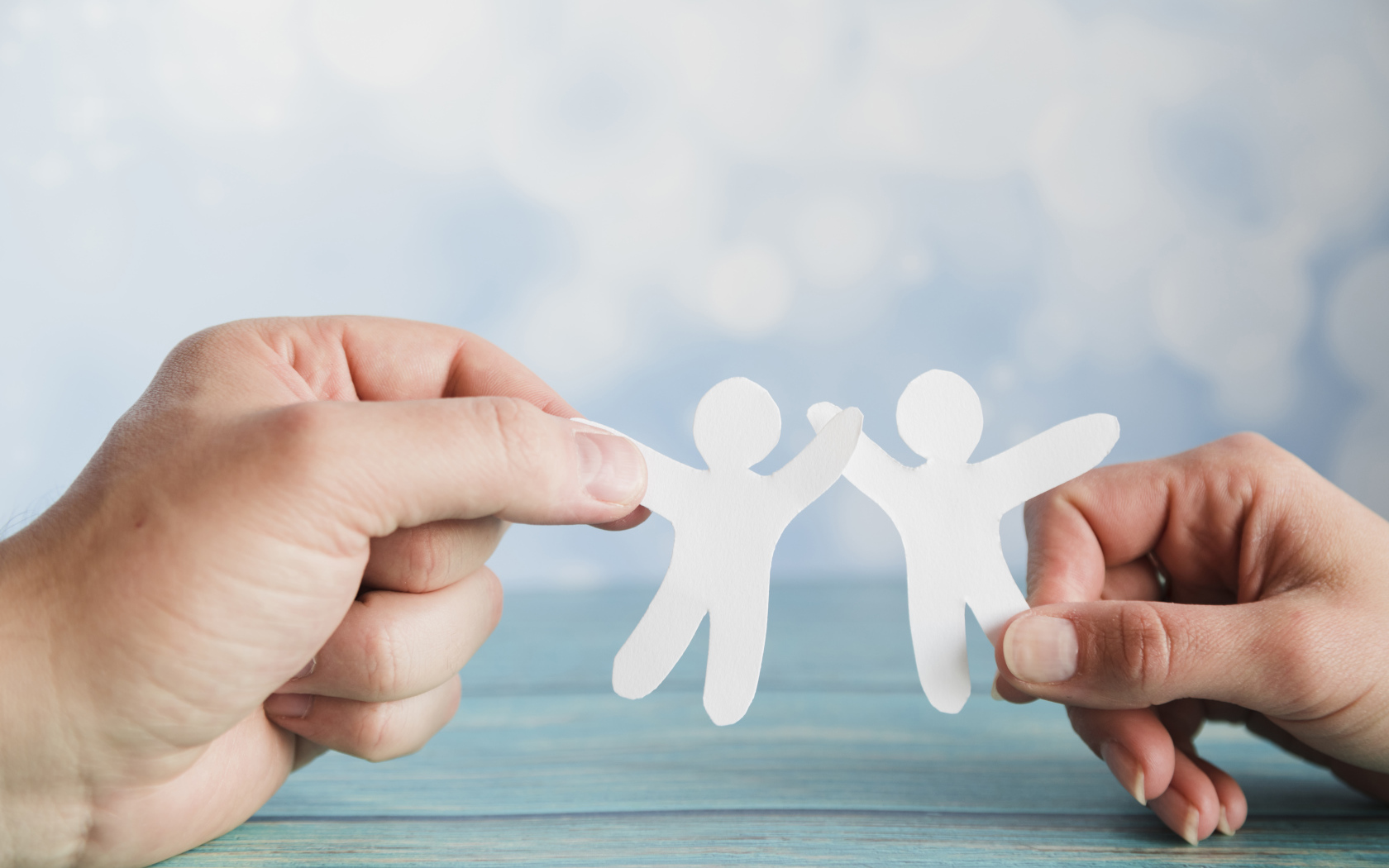 Два бумажных человечка в руках 