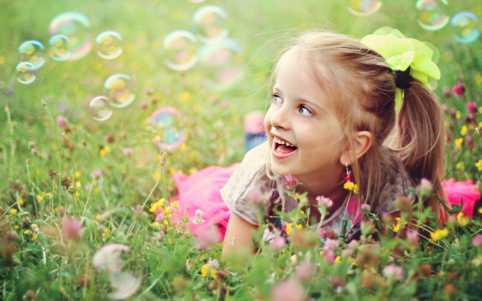 Cheerful girl lies on the grass with soap bubbles