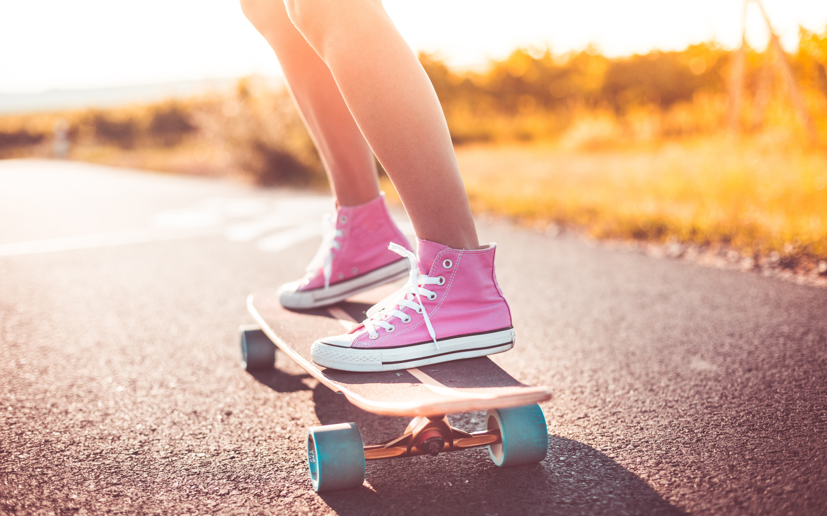 Девочка в розовых кедах едет на скейтборде
