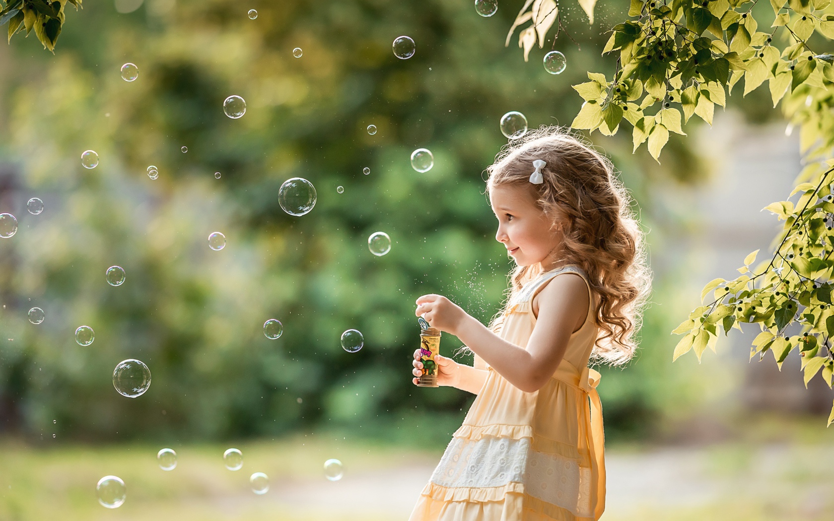 Маленькая девочка с мыльными пузырями в саду 