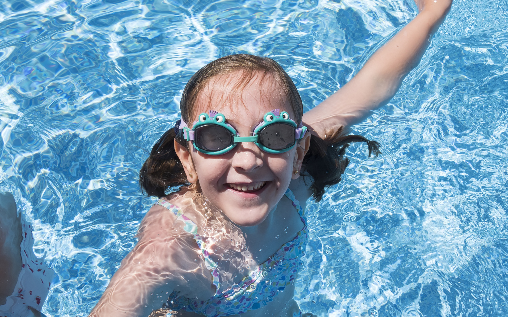 Маленькая улыбающаяся девочка в очках в бассейне 