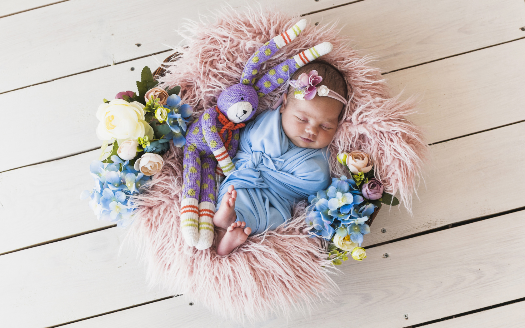 Спящий грудной ребенок с игрушкой в корзине 