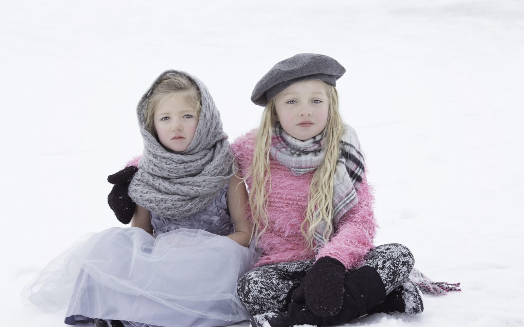 Две маленьких сестры сидят на снегу 