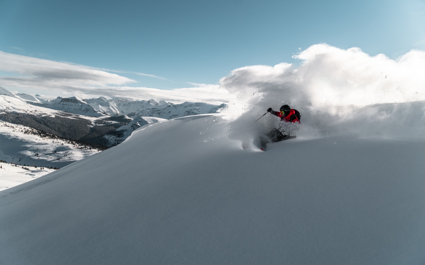 Мужчина спускается на лыжах с горы 
