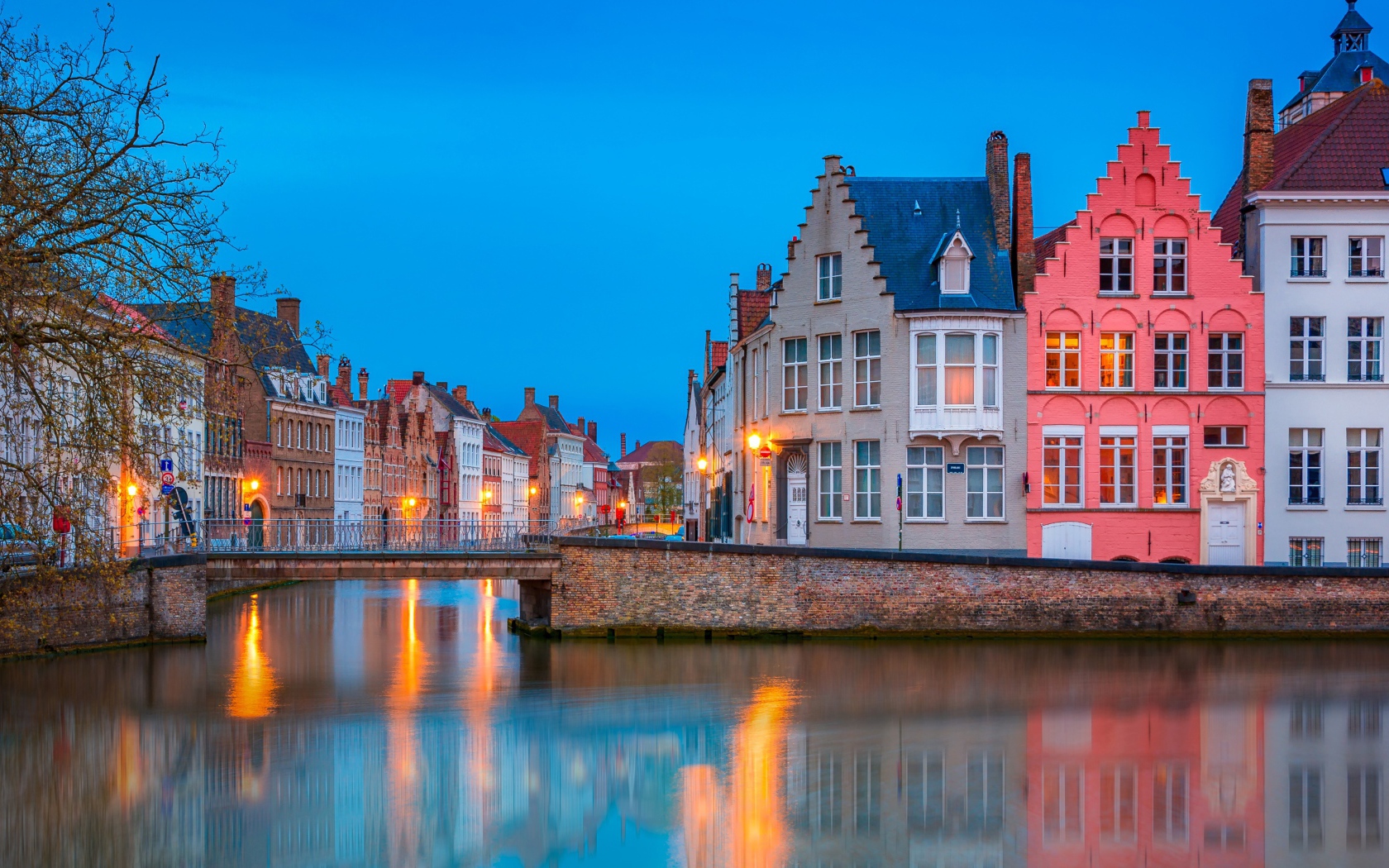 Большие дома и фонари отражаются в воде канала вечером