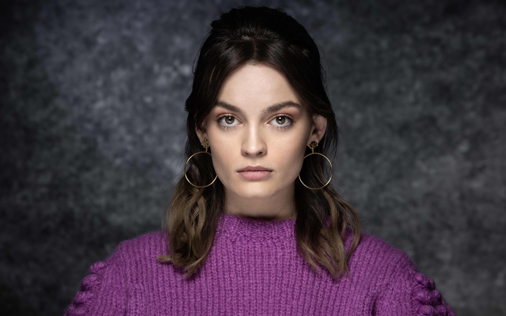Актриса Эмма Маккей в сиреневом свитере на сером фоне
