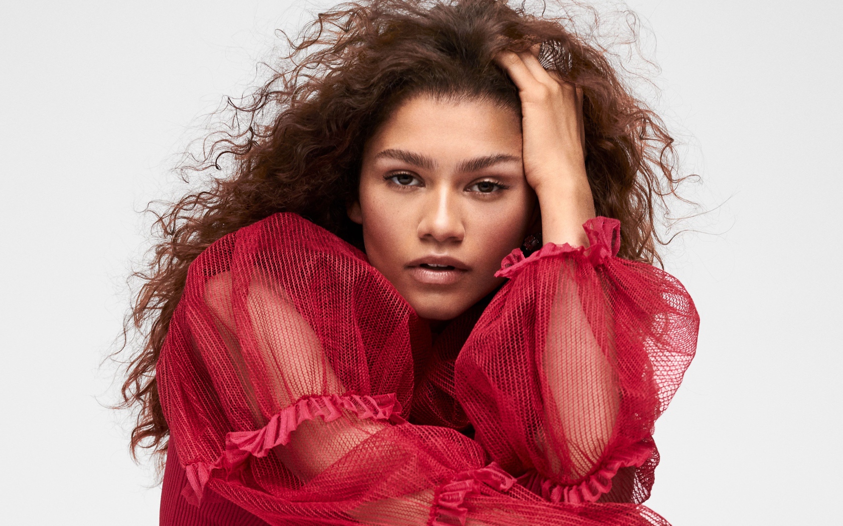 Кареглазая актриса Зендая в красном наряде с рукой в волосах