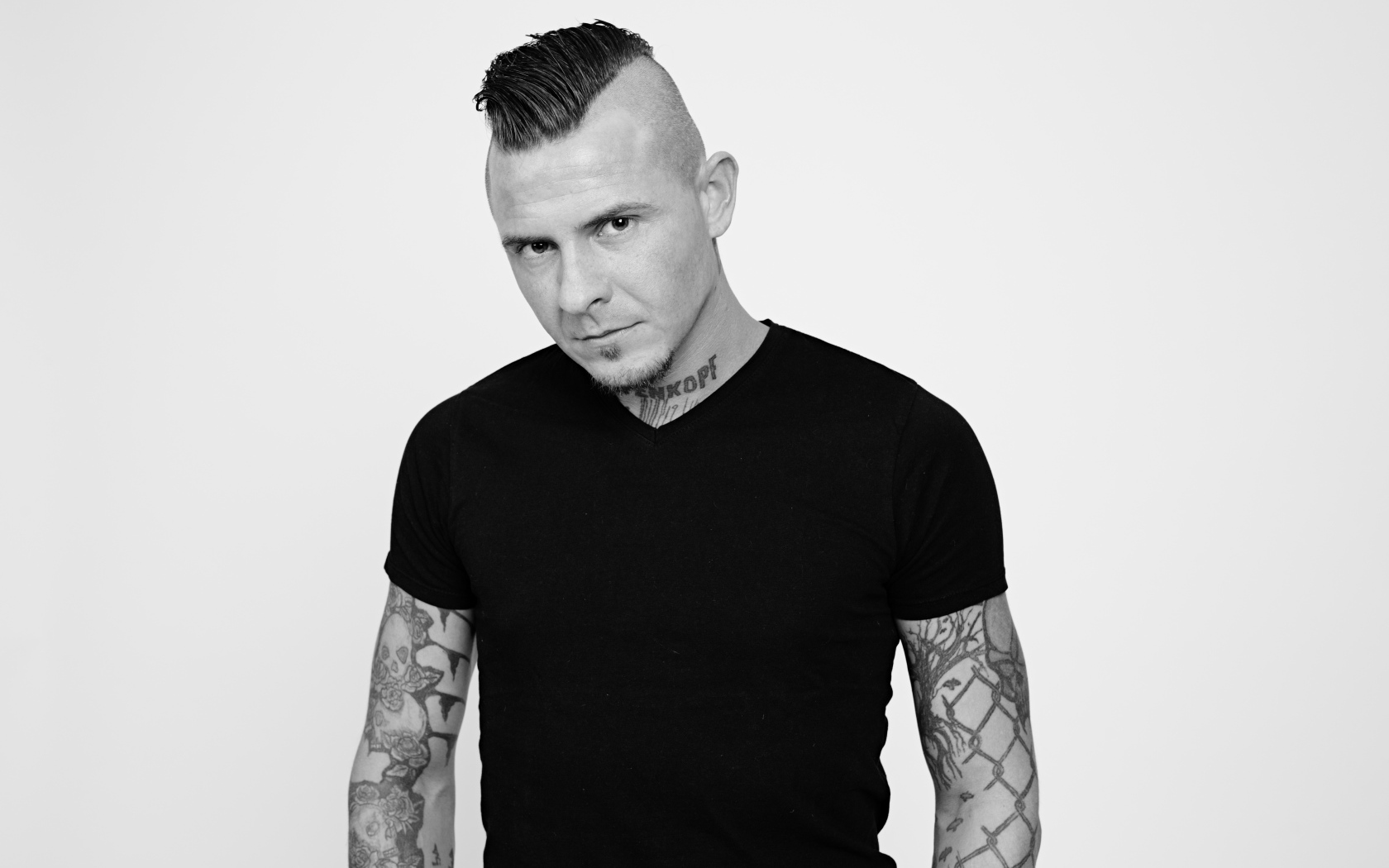 Мужчина в черной футболке с татуировками на теле